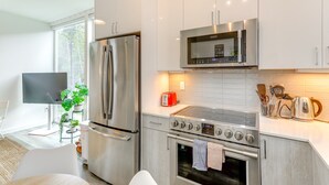 Een moderne keuken met roestvrijstalen apparatuur, een flatscreen-televisie en een groot raam.