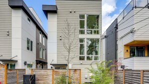Een modern meerlaags woongebouw met een plat dak, grote ramen en een houten hek.