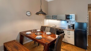 A modern kitchen with a dining table set for four, a microwave, a coffee maker, and a refrigerator. - DOWNTOWN - 2 Room Large Apartment (Praha)