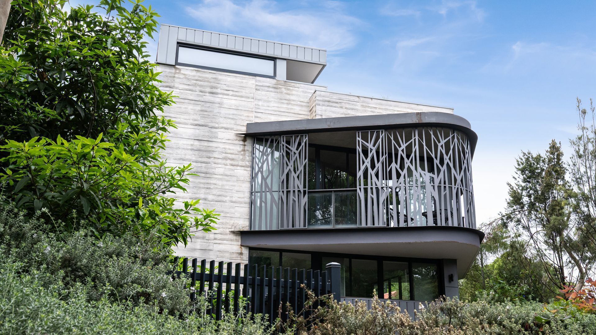 A modern building with a curved balcony, large windows, and a wooden facade.