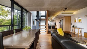Un interior moderno con comedor, sofá, escalera y cocina.
