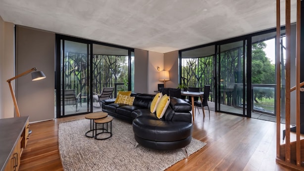 Una sala moderna con un sofá de cuero negro, una mesita redonda y un comedor con una silla.