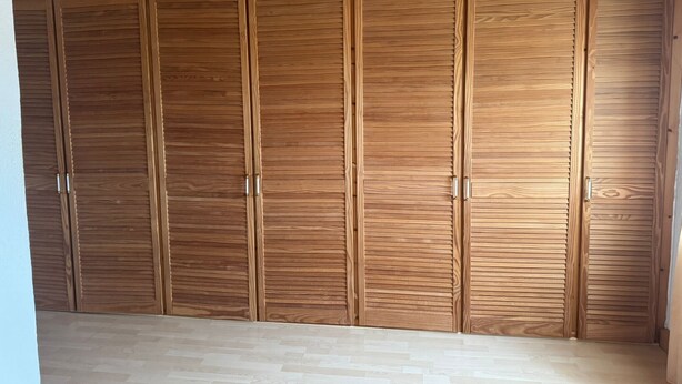 A wooden wardrobe with multiple doors and handles. - Apartment 'Beautiful 100m² Holiday' with Private Terrace, Shared Garden and Wi-Fi (Herford)