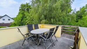 A patio with a round table and four chairs, surrounded by a wooden fence and lush greenery. - Apartment 'Beautiful 100m² Holiday' with Private Terrace, Shared Garden and Wi-Fi (Herford)