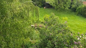 A lush garden with a variety of plants and trees, a wooden deck, and a clear view of the surrounding greenery. - Apartment 'Beautiful 100m² Holiday' with Private Terrace, Shared Garden and Wi-Fi (Herford)