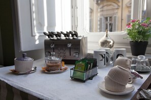 A table with a coffee machine, a teapot, a mug, a teacup, and a potted plant. - Bellini Palace The best b&b down town (Torino)