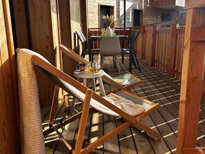 A wooden deck with a lounge chair, a small table with a teapot, and a chair with a vase. - Modern apartment with parking - 8 guests (Arâches-la-Frasse)