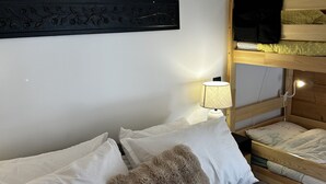 Un letto a castello con una televisione sul letto superiore, una lampada da comodino e un elemento decorativo a parete.