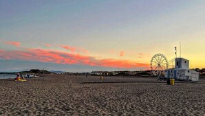 Une plage avec une grande roue et, au loin, un bureau de poste.