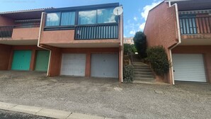 Un immeuble résidentiel de deux étages, doté d’une antenne parabolique, d’un balcon et d’un garage.