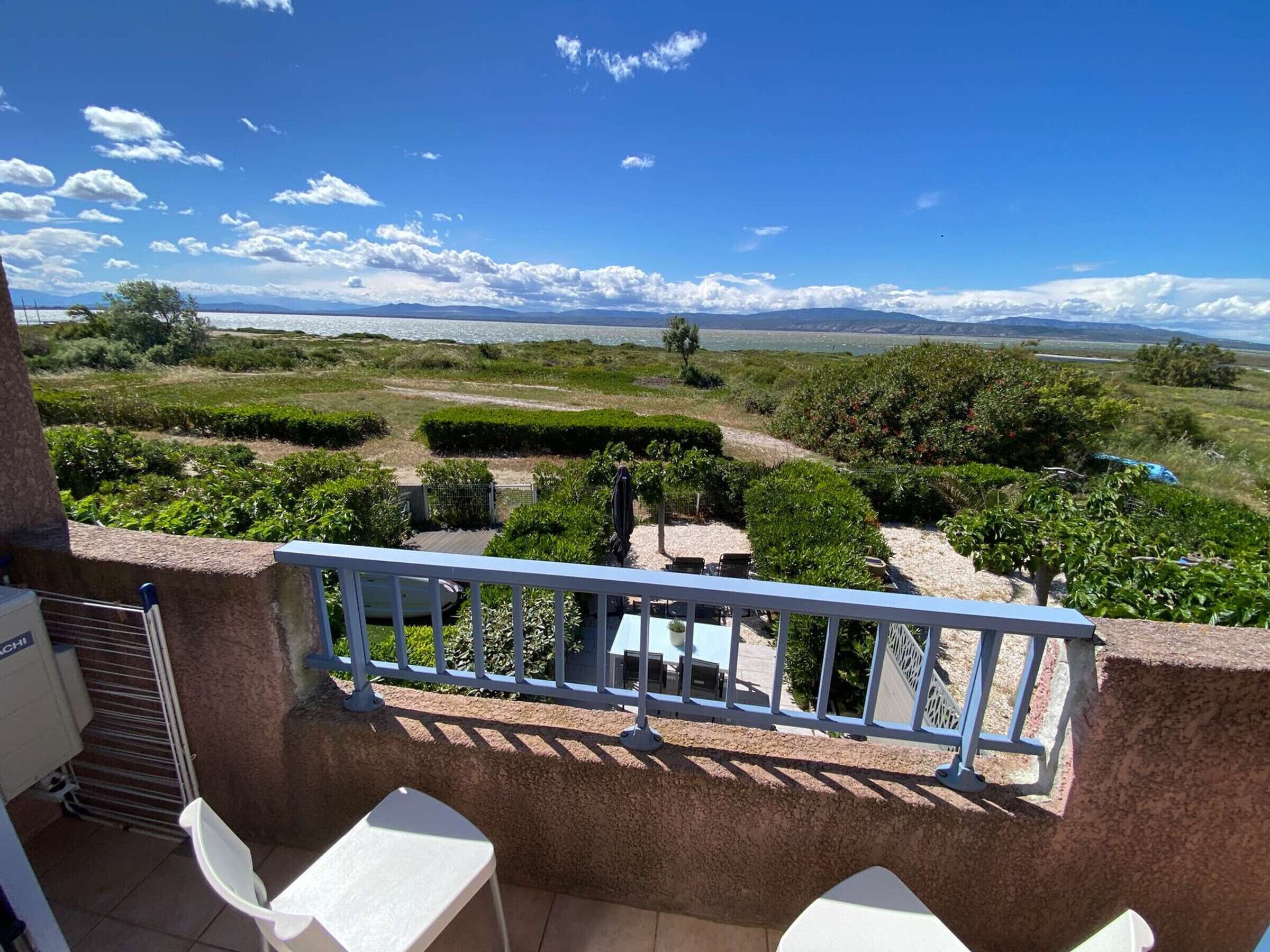 A balcony with a view of a landscaped garden and distant mountains.