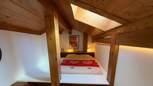 Een knus, klein slaapkamer op zolder met een schuine kap, een enkel bed, een nachtkastje en een ingelijst foto aan de muur.