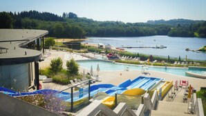 A swimming pool area with multiple pools, a beach, and a lake view.