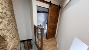 A staircase with a wooden handrail, a stone wall, and a wooden door.