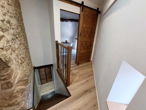 A staircase with a wooden handrail, a stone wall, and a wooden door. - Bluedothotel France (Magnac-Laval)