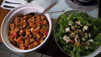 Two bowls of food on a table with a spoon and a glass.