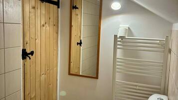 A bathroom with a wooden door, a mirror, a white sink, and a towel rack.