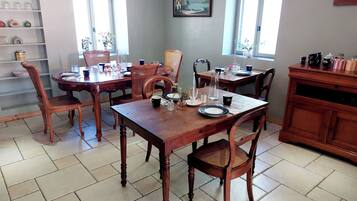 Un espace repas avec des tables et des chaises en bois, un sol carrelé et une fenêtre donnant sur un paysage agréable.