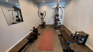A gym with exercise equipment, a mirror, and a red mat.