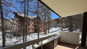 En balkon med udsigt over et sneklædt landskab og bygninger.