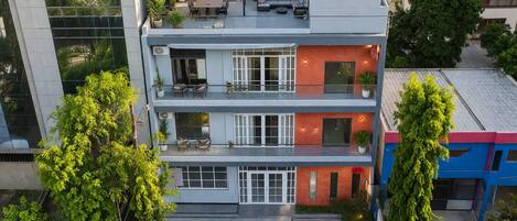A multi-story building with balconies, large windows, and a rooftop terrace.