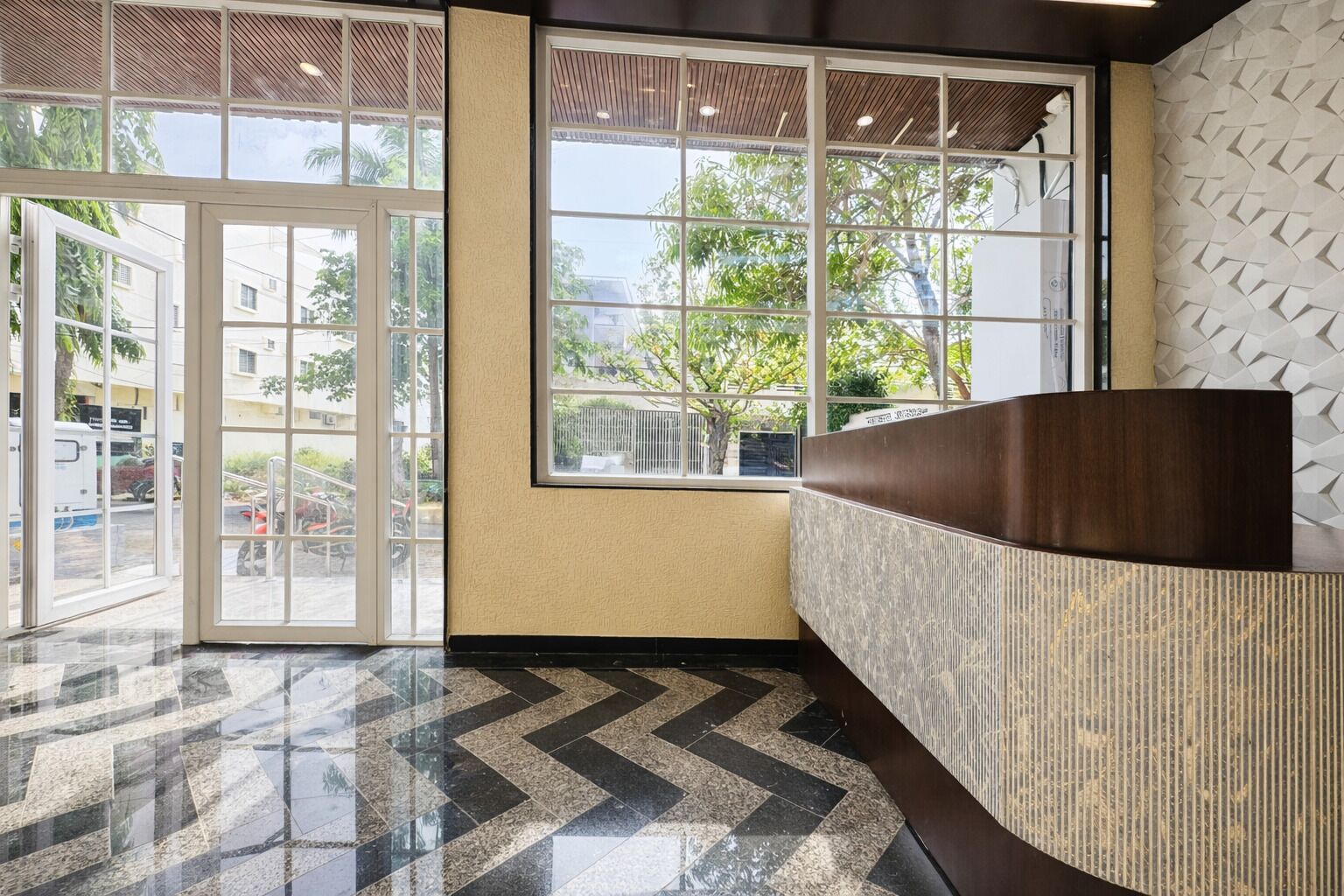 Un área de recepción con piso de mármol, ventanas amplias y mostrador de recepción.