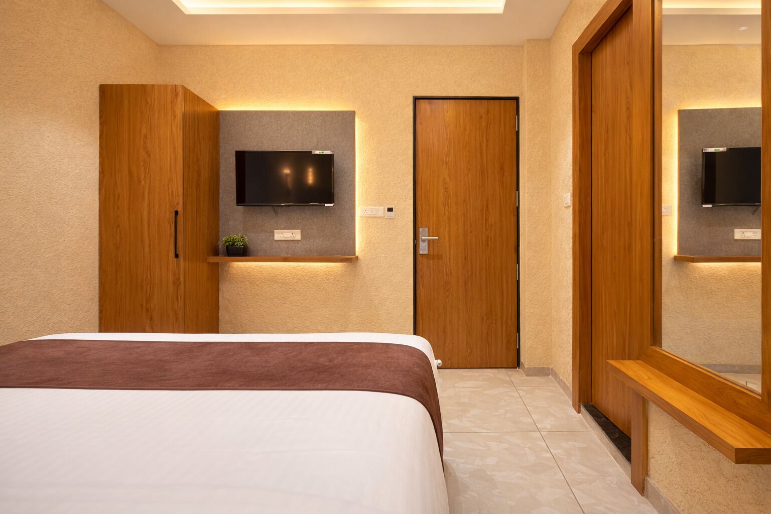 Une chambre à coucher avec un lit, un téléviseur fixé au mur et une armoire en bois.