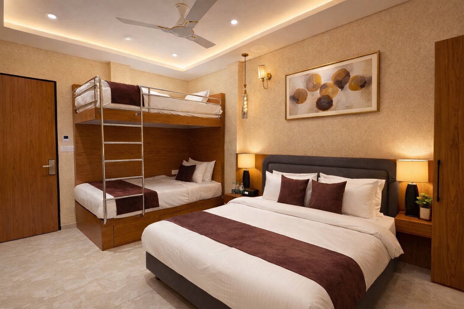 A hotel room with a bunk bed, a large bed, a ceiling fan, a wall-mounted light, and a painting.