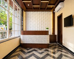 A reception desk with a patterned wall, a potted plant, and a television.