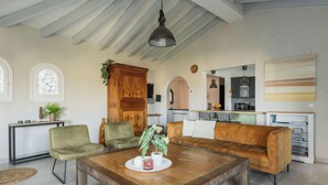 A spacious living area with a wooden coffee table, green and brown sofas, a dining table, and a kitchen in the background. - Villa MAGIA by Abahana Villas (Benissa)