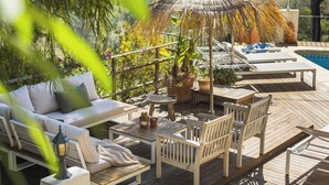 A wooden deck with outdoor furniture, a thatched umbrella, and a pool. - Villa MAGIA by Abahana Villas (Benissa)