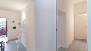 Ein Flur mit weißer Wand, einer Tür und einem weißen Regal.