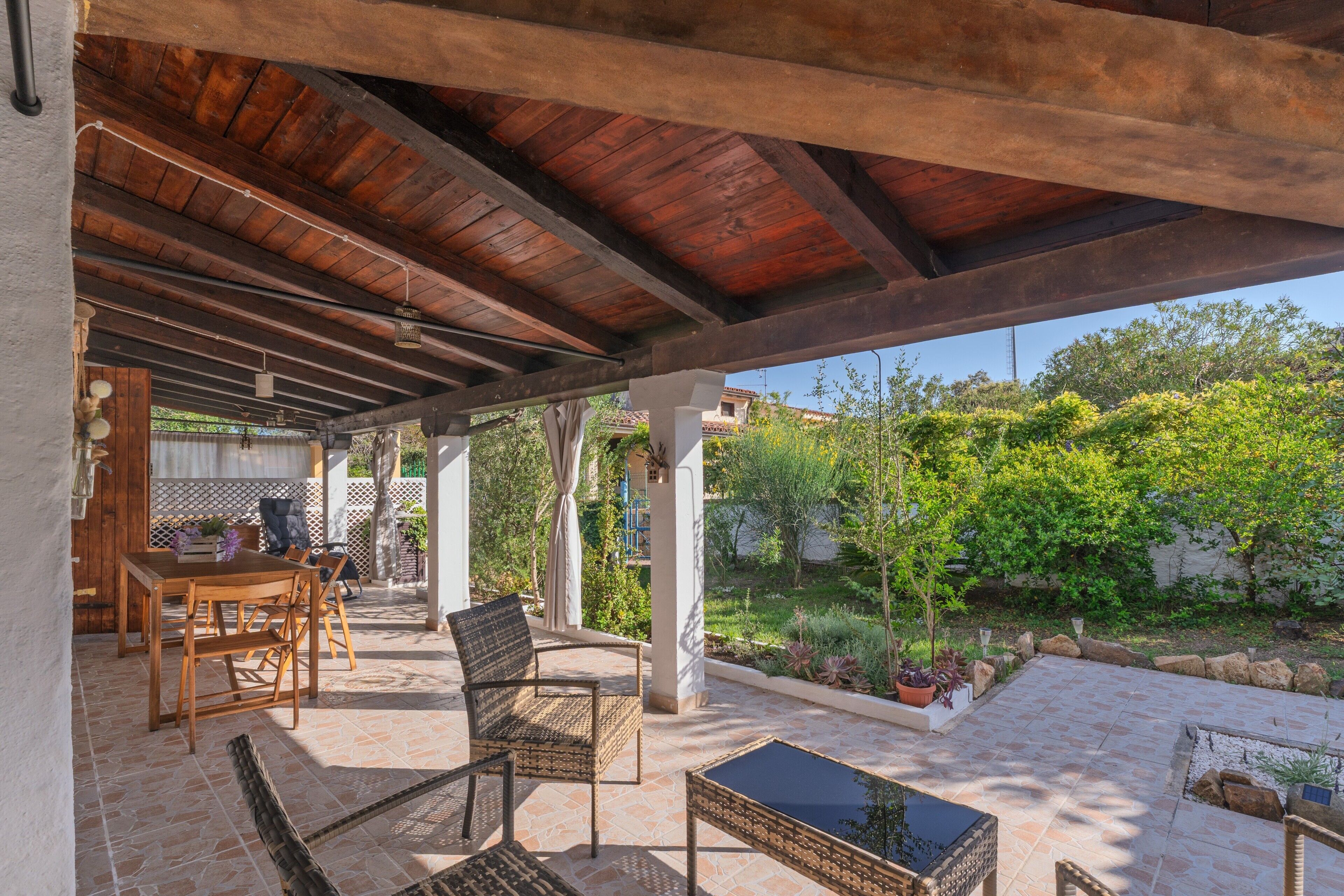 Eine Terrasse im Freien mit Holzmöbeln, einem Tisch und Blumentöpfen.