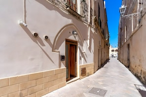 A narrow street with buildings on either side, a clear sky, and a building entrance with a door and window. - Apartment 'Sambiasi Vacanze' with Air Conditioning (Nardò)
