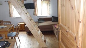 Interior rústico de cabana com um mezanino para dormir, uma mesa de jantar e cozinha.
