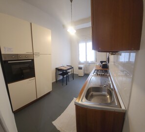 Eine kompakte Küche mit integriertem Backofen, Spüle und Essbereich mit Tisch und Stühlen.