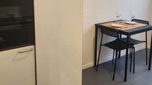 Keittiössä on sisäänrakennettu uuni, ruokapöytä tuoleineen ja pieni matto lattialla.