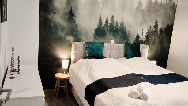 Une chambre à coucher comprenant un lit, un bureau, une chaise et une fresque murale représentant une forêt.