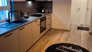 Une cuisine moderne avec un luminaire suspendu noir, une machine à café et un calendrier accroché au mur.