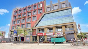 Un hotel a più piani con un cartello ben visibile 'HOTEL LEGENTA', uno spazio commerciale a livello terra e un'ampia facciata in vetro.