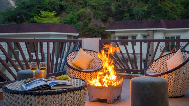A balcony with wicker chairs, a small fire pit, and a book. - ELIVAAS Serenita Abode Tranquil Escape (Bagradhauran)