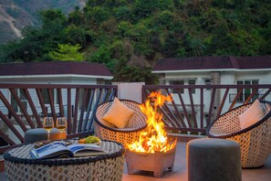 A balcony with wicker chairs, a small fire pit, and a book.