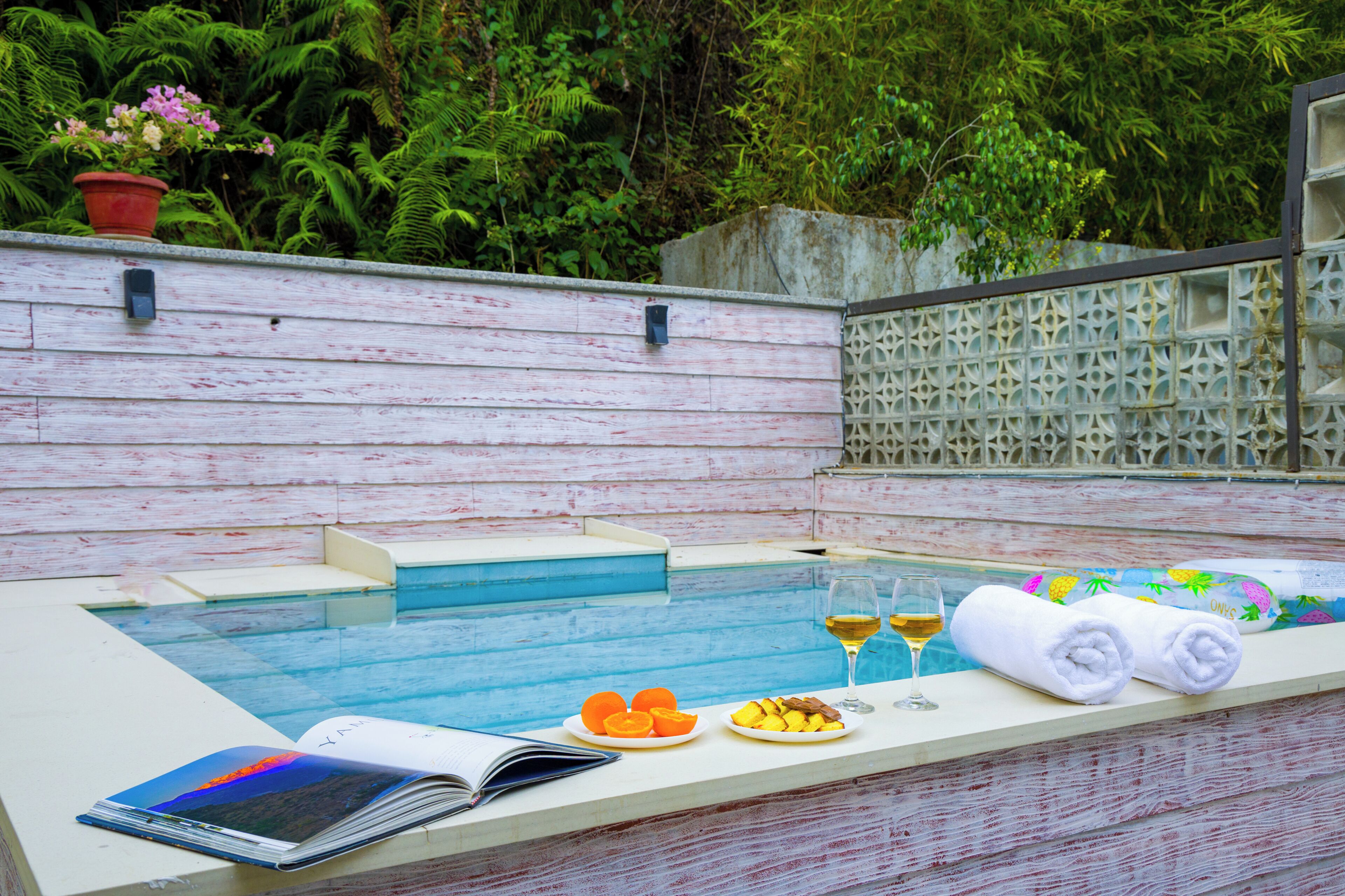 Ein Poolbereich mit Buch, Obst und Handtüchern.