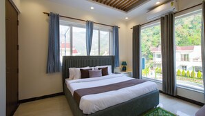 A bedroom with a large bed, a window with curtains, a bedside table with a lamp, and an air conditioning unit. - ELIVAAS Serenita Abode Tranquil Escape (Bagradhauran)