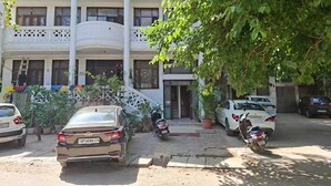 A multi-story building with a balcony, parked cars, and a motorcycle. - The Grey Leaf Residency (New Delhi)