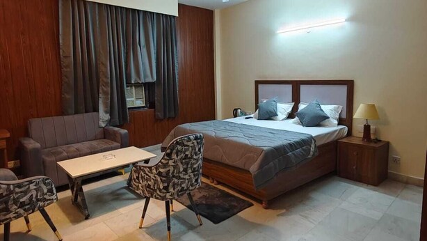 A bedroom with a bed, a sofa, a coffee table, and a chair. - The Grey Leaf Residency (New Delhi)