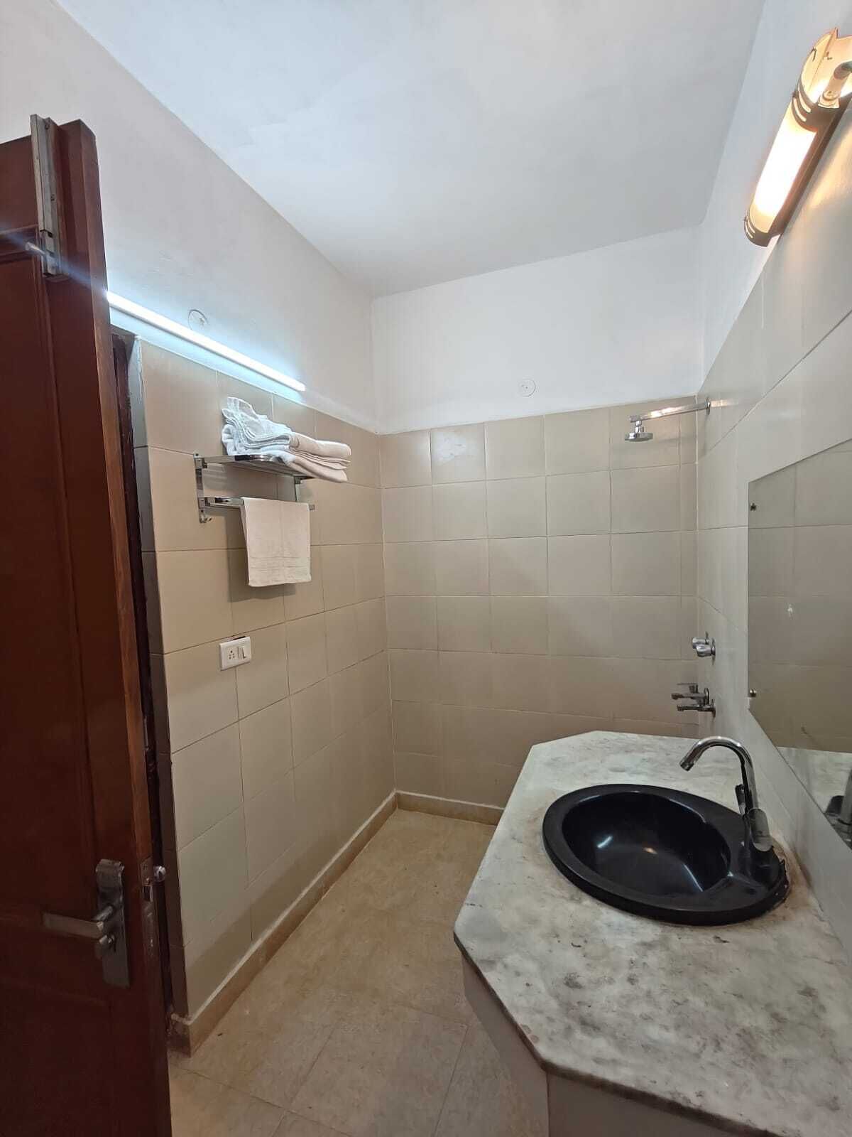 Ein Badezimmer mit Waschbecken, Spiegel, Handtuchhalter und Dusche.