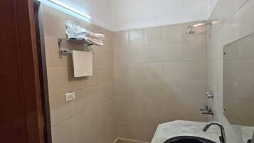 Ein Badezimmer mit Waschbecken, Spiegel, Handtuchhalter und Dusche.