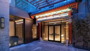 A traditional building with a modern glass entrance, a courtyard with a stone lantern, and a metal fence. - Manxin Mansion Beijing Shichahai Park Nanluoguxiang (Beijing)