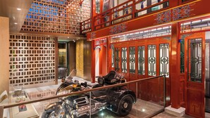 A multi-level interior with traditional architectural elements, a glass display case with a vintage motorcycle, and a modern staircase. - Manxin Mansion Beijing Shichahai Park Nanluoguxiang (Beijing)